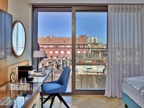 布达佩斯EST Grand Hotel Savoy的酒店客房设有一张书桌和一个大窗户。