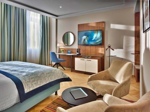 布达佩斯EST Grand Hotel Savoy的一间卧室配有一张床、一把椅子和一张书桌