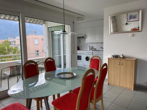 阿斯科纳Ascona: San Materno-Mary的一间设有玻璃桌和红色椅子的用餐室