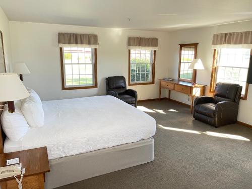 西普谢瓦纳Farmstead Inn and Conference Center的一间卧室配有一张床、两把椅子和一张书桌
