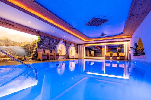 锡贝塔尔Hotel Bergkristall的蓝色灯光的酒店室内游泳池