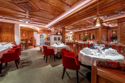 锡贝塔尔Hotel Bergkristall的一间设有白色桌子和红色椅子的餐厅