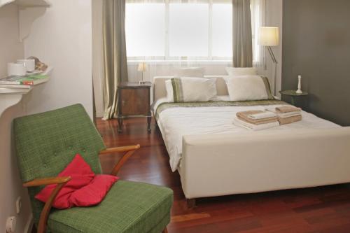 马托西纽什Apartamento Independente Praia & Porto - Limpo e Seguro的卧室配有白色的床和绿色椅子