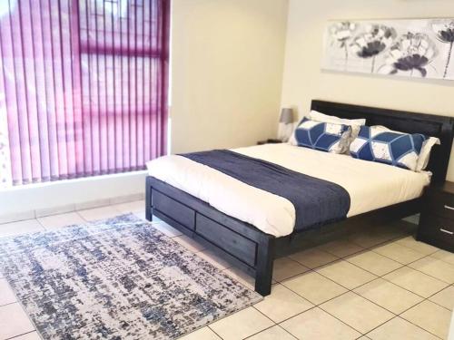 SandtonLuxurious Pvt Apartment ,Power backup, Pool & Jaccuzi的一间卧室配有一张带蓝色和白色枕头的床