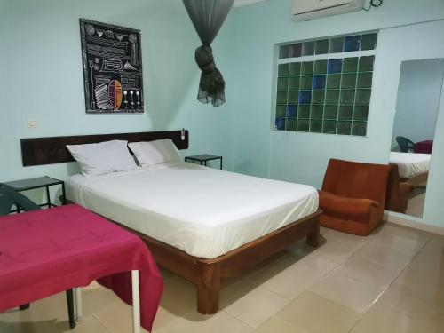 比绍HOTEL BADINCA Alojamento Low Cost in Bissau avenida FRANCISCO MENDES的卧室配有白色的床和椅子