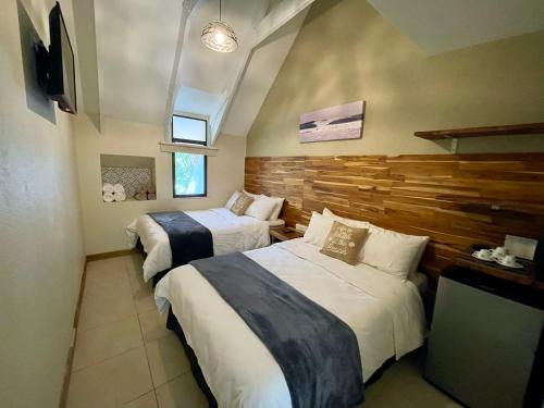 格兰德海滩Hotel El Manglar的一间卧室设有两张床和木墙