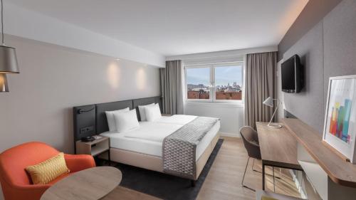 慕尼黑慕尼黑市中心假日酒店的酒店客房配有一张床、一张桌子和一把椅子。