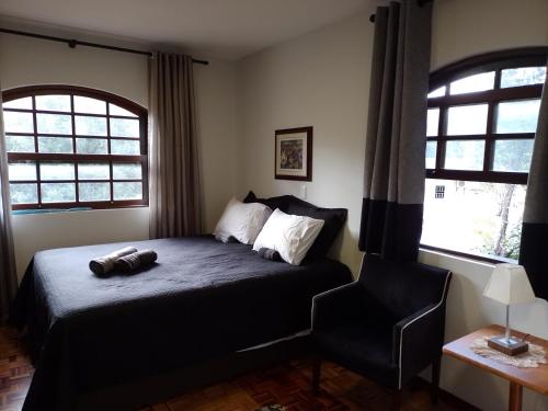 库里提巴Charming Home 2 min. from Barigui Park的一间卧室配有一张床和一把椅子,还有两个窗户