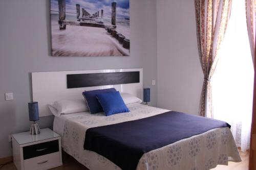 马德里Casa de Huéspedes Galaica的一间卧室配有一张带蓝色枕头的床和码头。