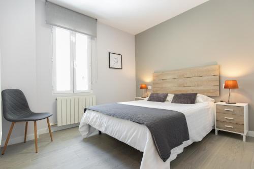 萨拉戈萨Apartamento Foro Romano的白色卧室配有一张大床和椅子