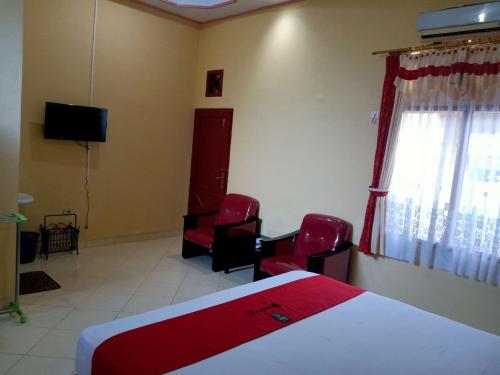 明古鲁省RedDoorz @ Puncak Tahura Hotel Bengkulu Tengah的一间卧室配有一张床、两把椅子和电视