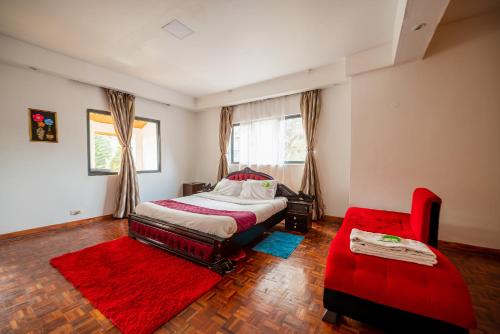 内罗毕spacious & stylish 4bdr kileleshwa的一间卧室配有一张大床和一张红色椅子