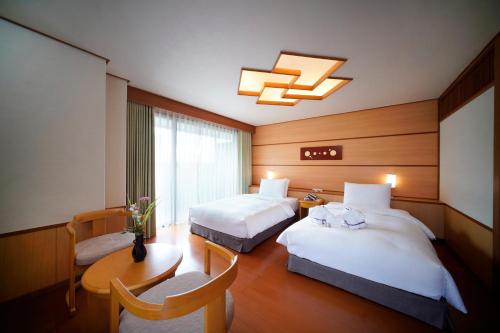 台北北投日胜生加贺屋国际温泉饭店的酒店客房设有两张床和一张桌子。