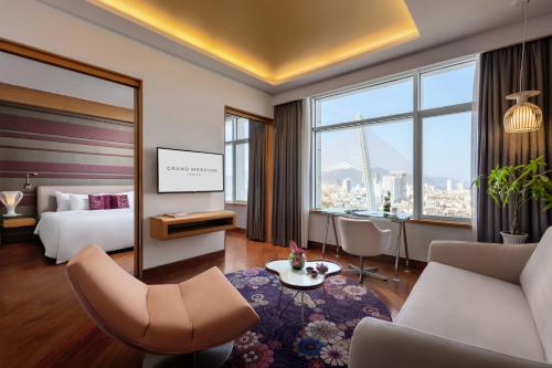 岘港岘港美爵酒店的酒店客房配有床、沙发和桌子。