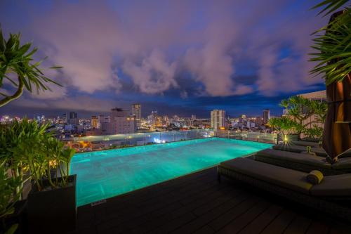 岘港LEGEND Boutique Hotel的一座在晚上拥有城市天际线的大型游泳池