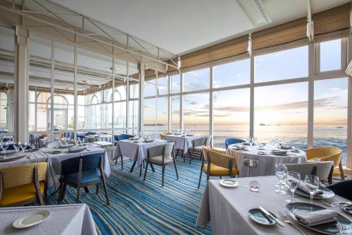 圣马洛格兰德酒店的餐厅设有桌椅和大窗户。
