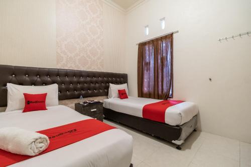 武吉丁宜RedDoorz Syariah at D'Ostha Residence的酒店客房设有两张床和窗户。
