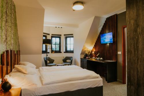 利贝雷茨Wellness Hotel Liberecká Výšina的酒店客房配有一张床、一张书桌和一台电视。