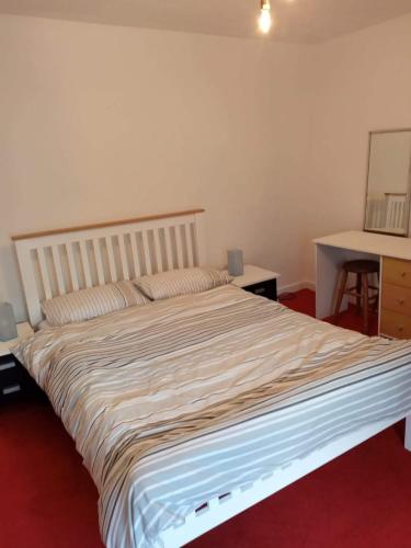 波斯考尔2 bedroom cottage in Porthcawl的一张大床,位于一间铺有红地毯的房间里