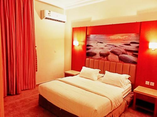 延布Taraf Yanbu 2的酒店客房设有一张床,墙上挂有绘画作品