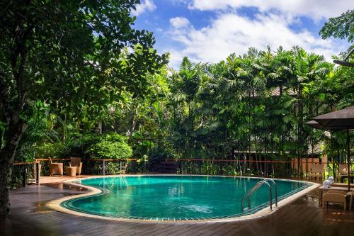 清迈Ratchapruek Lanna Boutique的一座大游泳池,位于一个树木繁茂的庭院内