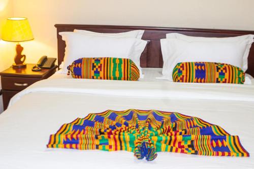 阿克拉Lou Ralph Hotel的一张床上,上面有一条色彩缤纷的毯子,还有电话
