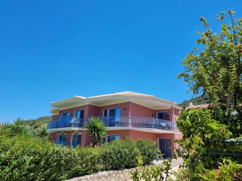 阿尔戈斯托利翁Julietta Suites的一座小山顶上树木繁茂的粉红色房子