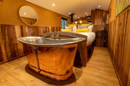 伍斯特Ashwood Shepherd Hut -Ockeridge Rural Retreats的浴室设有大型木制浴缸,位于床边