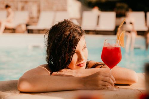 雅西Cardinale Resort的坐在游泳池里喝一杯的女人