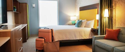 卡温顿Home2 Suites By Hilton Covington的配有一张床和一把椅子的酒店客房