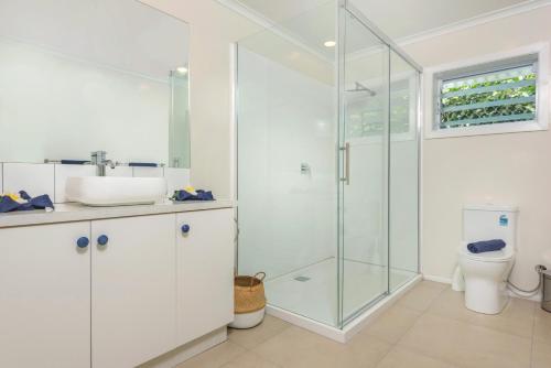 拉罗汤加Vaima Beachfront Apartments的一间带玻璃淋浴和卫生间的浴室