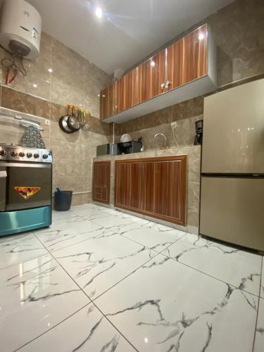 达喀尔Chez El Hadji et Hamidou的厨房铺有白色大理石地板,配有木质橱柜。