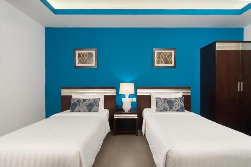 锡卜Al Hail Waves Hotel Managed By Centara的蓝色墙壁客房的两张床