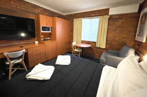 GuyraShiralee Motel Guyra的酒店客房设有一张大床和一台电视机。