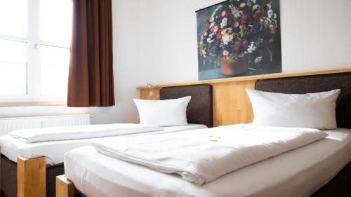 罗斯托克啤酒花市场酒店的配有白色床单的酒店客房内的两张床