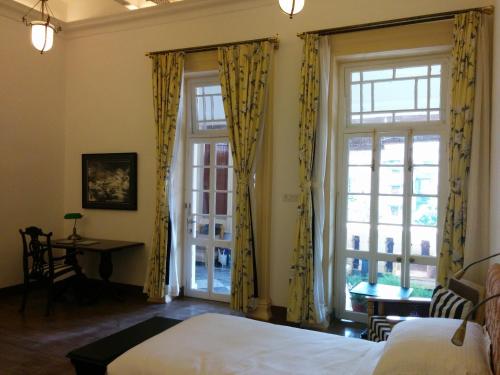 加尔各答哈灵顿住宿加早餐旅馆的一间卧室配有黄色窗帘、一张床和一张书桌