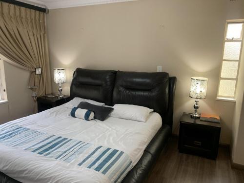 约翰内斯堡Safari Apartments -Beautiful 3 bedrooms, 10-seater dining , TV room, Garden & Pool的卧室内一张带黑色皮革床头板的床