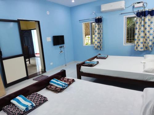蓬蒂切里Sri Sai Farm House的蓝色的客房配有两张床和镜子