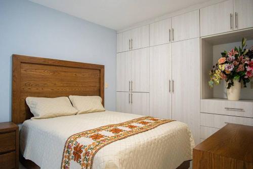 乌鲁阿潘San Felipe Apartament的一间卧室,配有一张床和花瓶