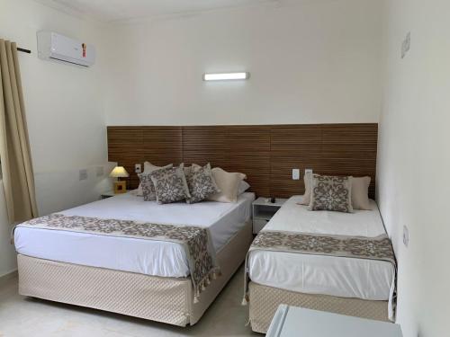 瓜鲁雅Pousada Pé na Areia Guarujá的一间卧室配有两张床和床头板