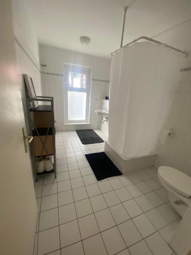 柏林Osthafen II的白色瓷砖浴室设有卫生间和窗户。