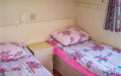 达尔沃沃Lovely stacaravan In Darlowo With Kitchen的小客房内的两张床和粉红色床单