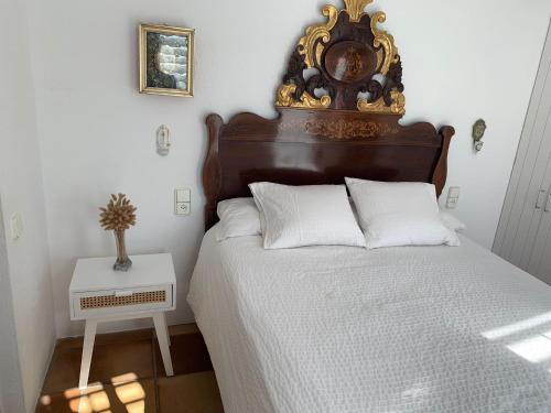 卡达克斯Es Forn - Cadaqués的一张带木制床头板和墙上时钟的床