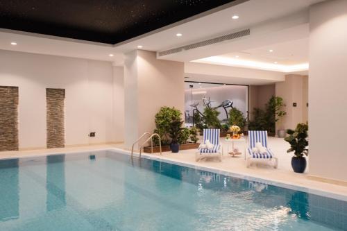 利雅德Cantonal Hotel by Warwick的游泳池旁设有2把蓝色和白色椅子