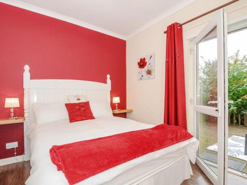 海尔The Station Masters Lodge的红色的卧室设有白色的床和窗户。