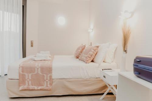 特里卡拉Quattro Luxury Apartments的白色卧室配有带粉色和白色枕头的床
