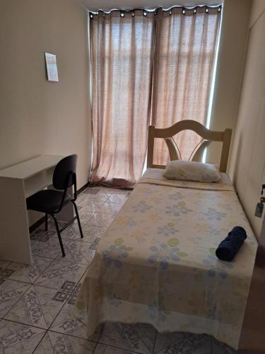 巴西利亚Pousada do Luquinhas的一间卧室配有一张床、一张书桌和一个窗户。