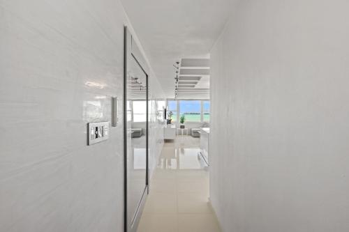 圣胡安Amapola SeaSide Beach Front Apartment的一条带白色墙壁和玻璃门的走廊