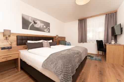 厄茨Alpenchalet Oetztal的一间卧室配有一张床、一张书桌和一台电视