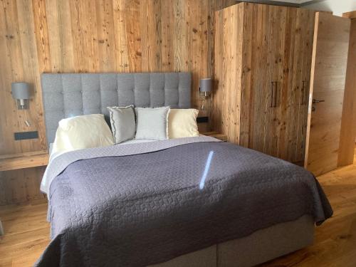 蒂罗尔-基希贝格Lodge14的一间卧室配有一张带木墙的大床